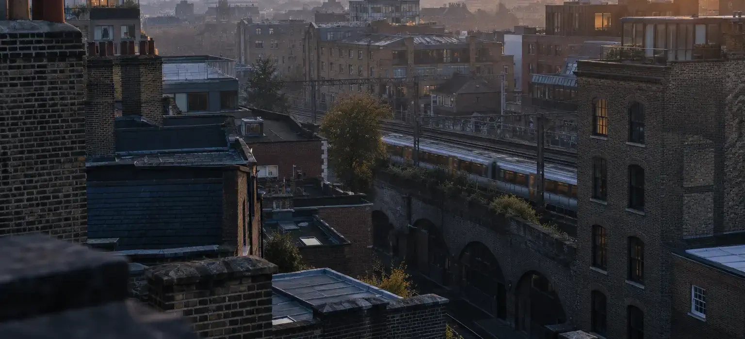 London rooftops at dusk with a railway viaduct and a passing train near Farringdon.